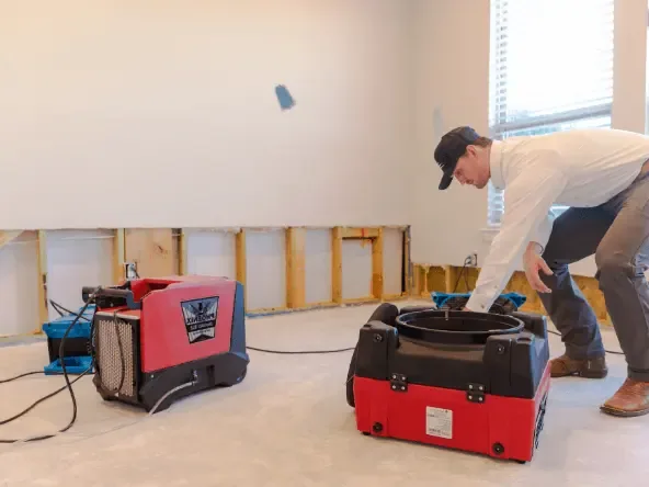 Technician placing drying equipment in a flood-cut room