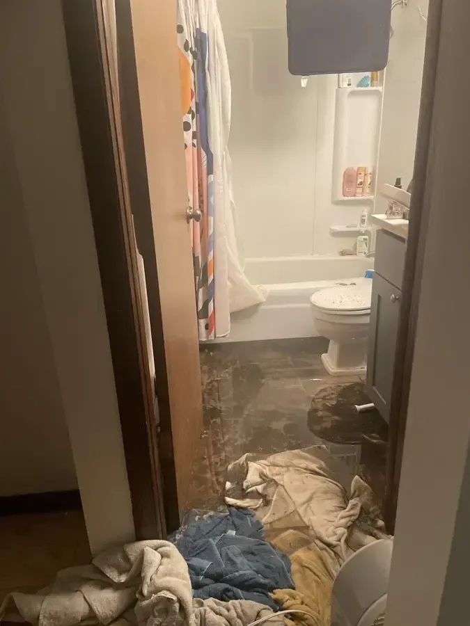 Bathroom floor covered by a sewage backup with soiled towels